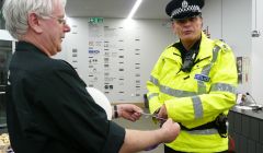 Stuart Hubbard holds out the Mareel opening ribbon for PC Barry Derbyshire to cut at Saturday's all day opening ceremony. Pic. Shetland News