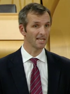 Orkney MSP Liam McArthur delivering Tavish Scott's speech in the Scottish Parliament on Tuesday - Photo: Holyrood TV