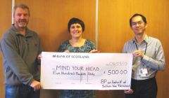 The terminal's charity appeals committee chairman Graham Hughson (left) hands Anouska Civico of Mind Your Head the big cheque, with instrument and control engineer Andrian Harsono.