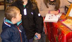 Elsbeth Stewart Clark signs a copy of her book Robin's Red Christmas for three-year-old Filip and Sonia Poniecki, aged eight, in the Aywick Shop at the start of her book signing tour of the isles – Photo: Charlie Inkster
