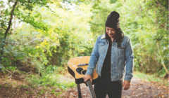 Lucy Spraggan and her guitar in the woods.