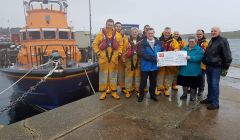 Members of the Lerwick Lifeboat crew accepting George and Wilma Miller's generous golden wedding gesture.
