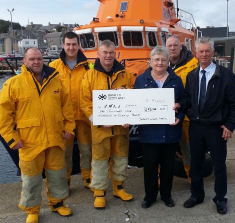 Lerwick lifeboat coxswain Alan Tarby (centre) accepts the donation from Alan and Sunniva Leask. Looking on are from left to right crew members Ian Harms, Grant Masson and John Best. Photo: RNLI