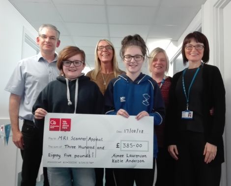 Katie Anderson and Aimee Laurenson handing over a cheque to NHS staff.