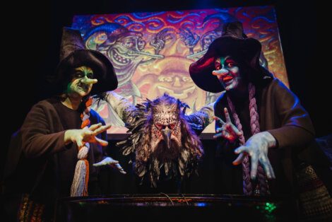A group of people dressed as witches are posing in front of a painting.