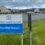Sign reading "Shetland Islands Council Brae High School" in front of school buildings with cloudy sky in the background.