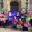 A group of people stand outside holding signs that read “PAY ATTENTION” and “OFFICIAL PICKET” with a banner that says "eis Shetland Local Association." They are protesting in front of a building.