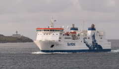 A large ferry named "NorthLink" sails in open water, with a lighthouse visible in the background. © Austin Taylor Photography, 2023.