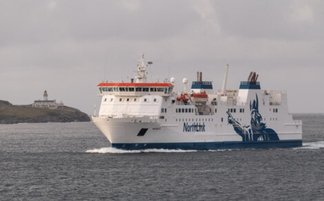 A large ferry named "NorthLink" sails in open water, with a lighthouse visible in the background. © Austin Taylor Photography, 2023.