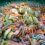 A dense underwater scene showing numerous colorful brittle stars layered over green and pink rocks.