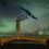 A tidal turbine stands against a backdrop of green aurora borealis in a dark night sky.
