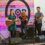 A band performs on stage with a drummer, guitarist, violinist, and bassist in front of a backdrop that reads "The Pop.