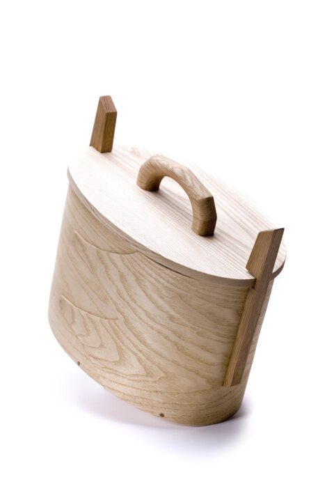 Wooden barrel-shaped container with a lid and handle, tilted at an angle, against a white background.