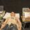 A man lies on a medical bed connected to various electrodes while a healthcare professional analyzes data from a monitor.