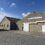 A concrete building with a sign reading "Shetland Global Seafood Ltd," featuring a large garage door and a smaller entrance, under a partly cloudy sky.