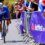 Cyclist in blue racing uphill past a cheering crowd behind barriers with NatWest branding.