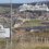 A road sign welcomes visitors to Lerwick, with a large cruise ship docked in the background and the town spread out along the coastline.