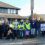 Group of people with signs on a picket line during a strike, wearing vests and displaying union affiliation.