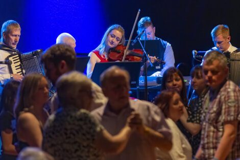 Musicians perform live as couples enjoy a dance on the floor.