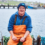 A man in overalls sitting on a boat.