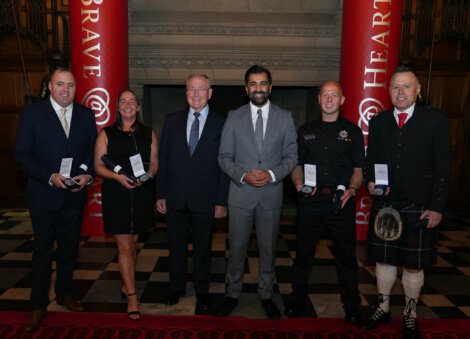 Group of individuals posing with awards at an event.