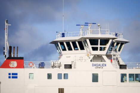 The bridge of a ferry named 'daggalien' with the destination 'lerwick' displayed, against a backdrop of a cloudy sky.
