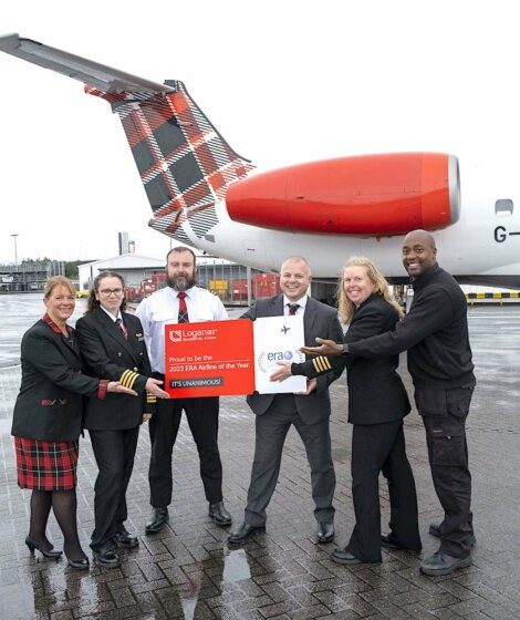A group of airline personnel holding an award in front of an aircraft with a distinctive tail design.