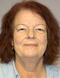 A headshot of a smiling middle-aged woman with reddish-brown hair and a blue shirt.