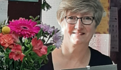 A woman with glasses holding a bouquet of flowers.