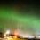 A green aurora bore over a city.