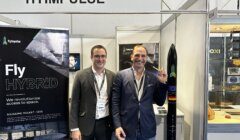 Two men standing in front of a booth at a trade show.