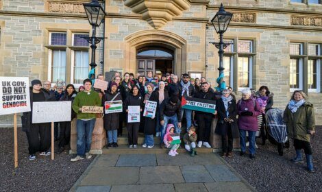 A group of people holding signs in front of a building.