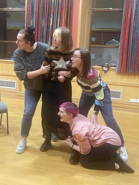 A group of women posing for a photo in a theatre.