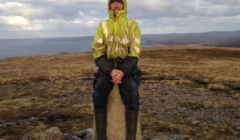 A man sitting on a stone pillar.