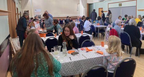 A group of people sitting at tables in a large hall.