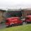 Two red vans parked in front of a building.