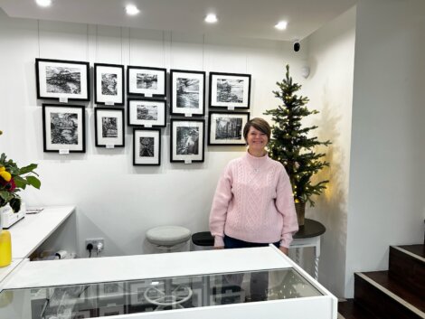 A woman standing in front of a counter with framed pictures.