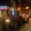 A tractor driving down a street with lights on it.