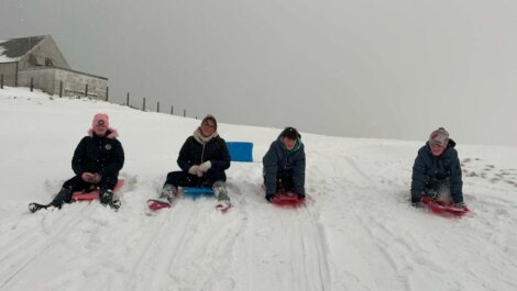 A group of people sledding down a snowy hill.