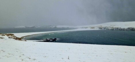 A beach covered in snow near a body of water.