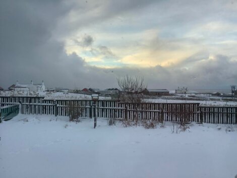 A snowy scene with a fence in the background.