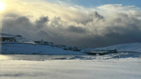 The sun is shining over a snow covered hill.