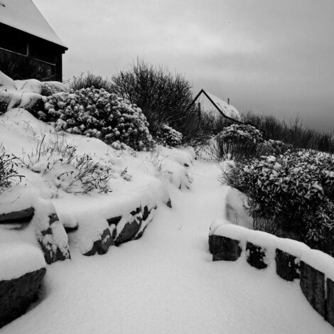 A black and white photo of a house covered in snow.