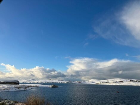 A snow covered lake with a blue sky in the background.