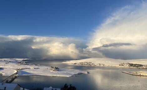A view of a snow covered lake with a cloud in the sky.