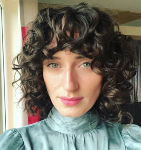 A woman with curly hair is posing for a photo.