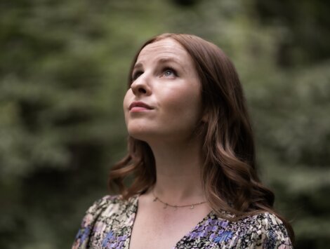 A woman in a floral dress looking up at the sky.