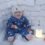 A baby sitting in the snow with a candle.
