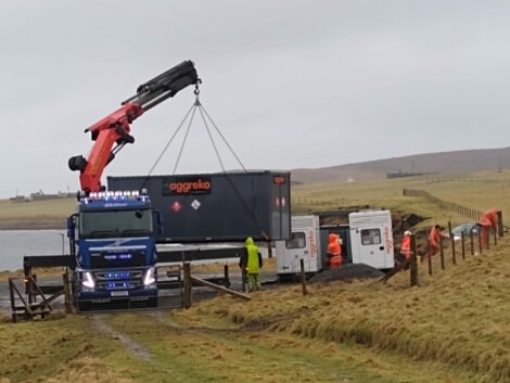 A truck with a crane lifting a large container.