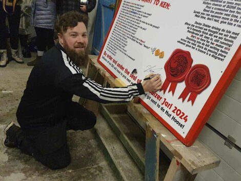 A man with a beard writing on a sign.